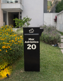 Caixa de correio Vinhedo preta com iluminação LED acesa à noite em jardim com flores